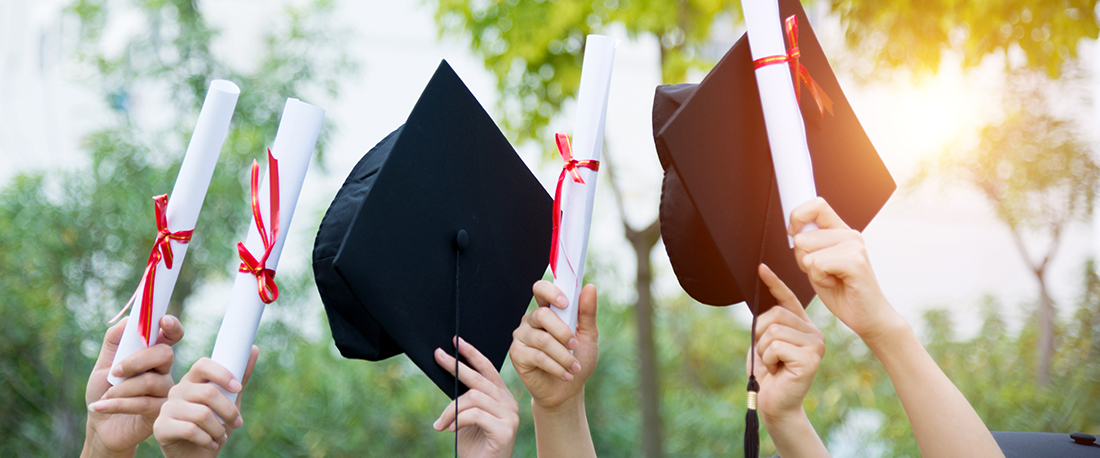 Group of graduate students holding their motarboards and diplomas.