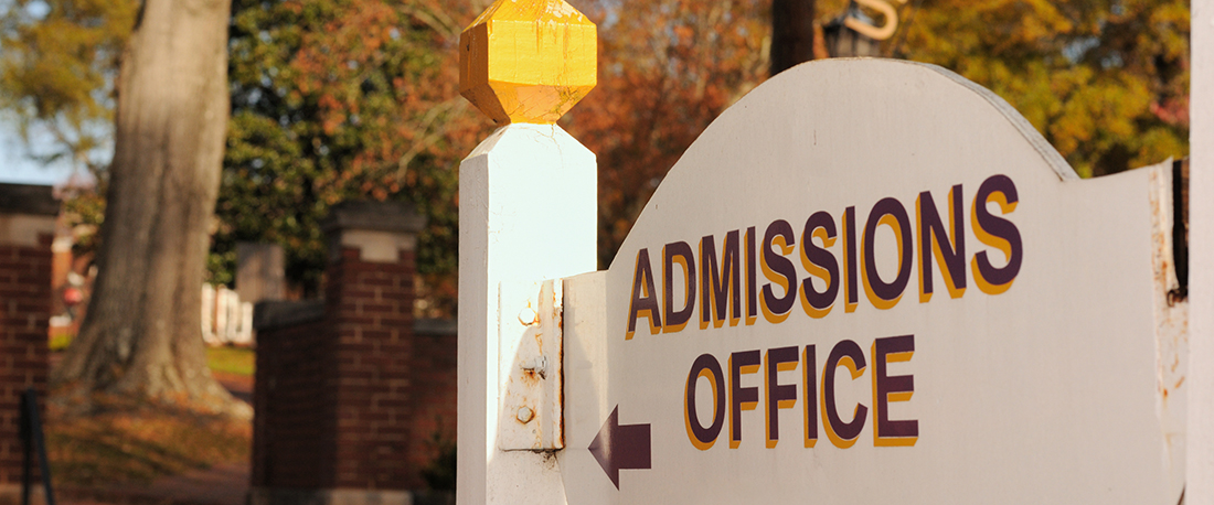 Directional sign for admissions office under arched university sign
